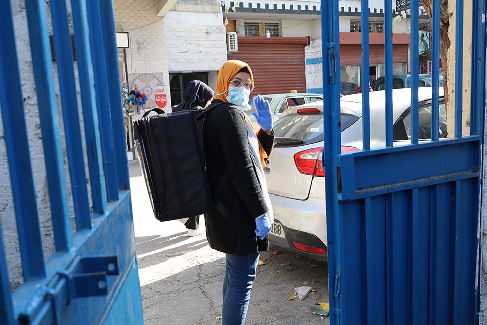 Safa, 25, a community worker at Initiate and Women Program Association’s community kitchen, distributes hot meals to food-insecure households in Ein El Helweh camp, Saida, Lebanon. Photo: Anas Chehab/Initiate.