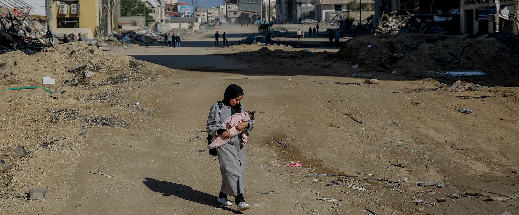 Salma, a 29-year-old, carries her infant while walking on Rashid Street, west of Gaza City, on 11 January 2024.