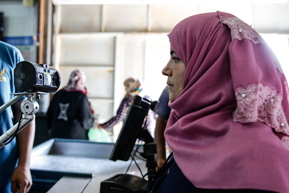 Before the lockdown went into effect, a UN Women beneficiary gets her iris scanned, allowing her to buy groceries at the Sameh Mall Supermarket in Azraq refugee camp, Jordan. Photo: UN Women/Lauren Rooney