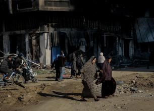 Two women cross the road and are surrounded by destroyed buildings on al-Jalaa Street in the centre of Gaza City on 11 January 2024. 