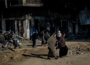 Two women cross the road and are surrounded by destroyed buildings at al-Jalaa Street in the center of Gaza City on 11 January 2024.