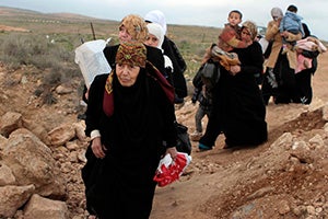 A line of Syrian refugee women, some carrying children, cross into Jordan from southern Syria in February 2013. Photo credit: UNHCR/N. Douad